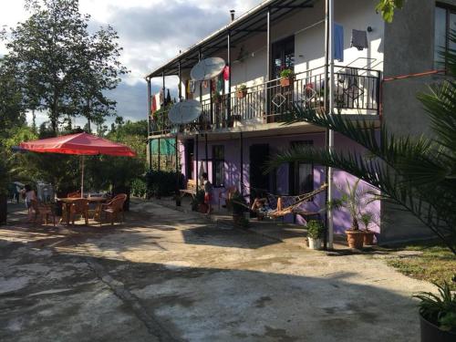 a building with a patio with a table and an umbrella at family hotel our house in Ts'ikhisdziri