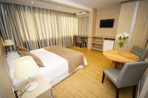 um quarto de hotel com uma cama, uma mesa e uma televisão em Hotel Geranium em Balneário Camboriú