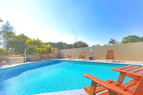 a swimming pool with chairs and a picnic table at Capricorn One Beachside Holiday Apartments - Official in Gold Coast