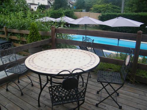 a table and chairs on a deck next to a pool at Les Charmois - Spa privatif en supplément et sur un autre site in Bains-les-Bains