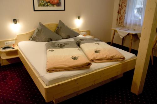a bed with two pillows on it in a room at Pension Backstuba in Partenen