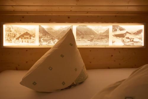 a bed with two pillows and a window with mountains at Pension Backstuba in Partenen