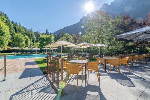 a restaurant with tables and chairs next to a pool at Hotel La Maison Wellness & Spa in Alleghe