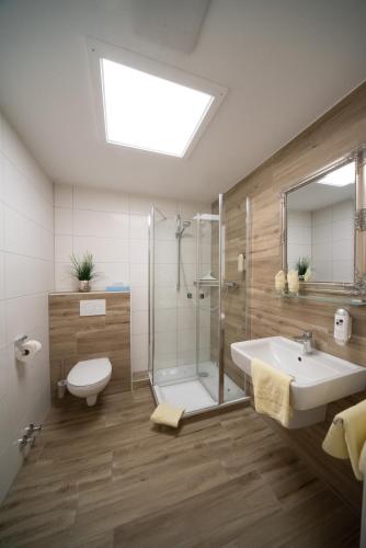 a bathroom with a shower and a sink and a toilet at Hotel Garni Zum Grünen Baum in Hövelhof