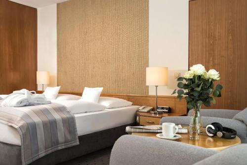 a bedroom with a bed and a vase of flowers on a table at Maritim Airport Hotel Hannover in Hannover
