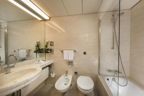 a bathroom with a sink and a toilet and a shower at Maritim Airport Hotel Hannover in Hannover