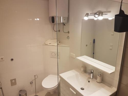 a white bathroom with a toilet and a sink at Sea view apartment with a huge terrace in Pisak