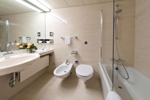 a bathroom with a toilet and a sink and a shower at Maritim Airport Hotel Hannover in Hannover