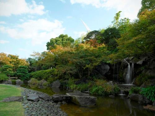 a pond in a garden with a waterfall at Hotel Okura Kobe in Kobe