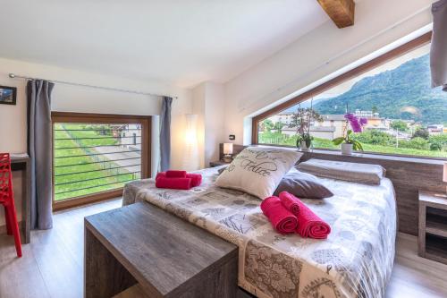 a bedroom with a bed with red pillows and a large window at B&B Valtellina Mon Amour in Piateda