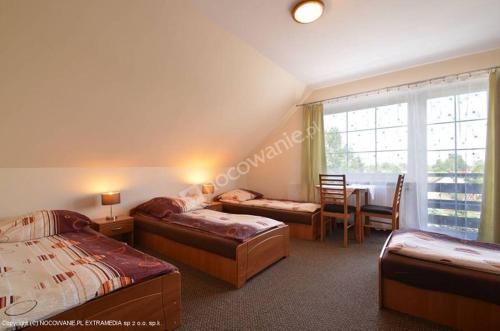 1 Schlafzimmer mit 2 Betten, einem Tisch und einem Fenster in der Unterkunft Restauracja Applause in Ludwin