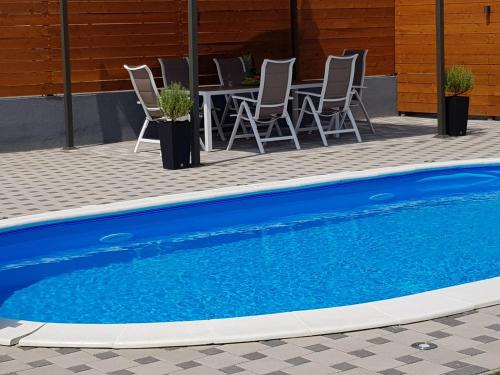 a blue swimming pool with chairs and a table at "Oasis of Peace Zagreb-Apartments" in Zagreb