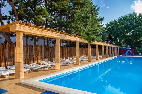 a swimming pool with a pavilion and chairs next to a fence at Olimp Resort Hotel All Inclusive in Anapa