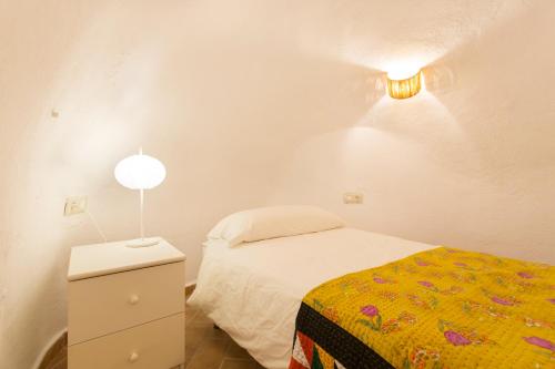 a small white bedroom with a bed and a lamp at Montes Claros 26 in Granada