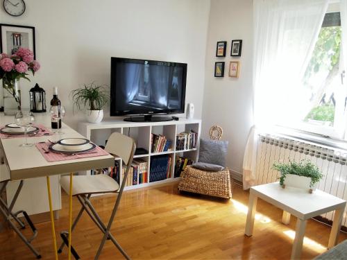 ein Wohnzimmer mit einem TV, einem Tisch und Stühlen in der Unterkunft Chic apartment in Zagreb
