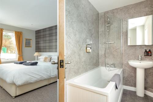 y baño con cama, bañera y lavamanos. en Highland Holiday Cottages en Newtonmore