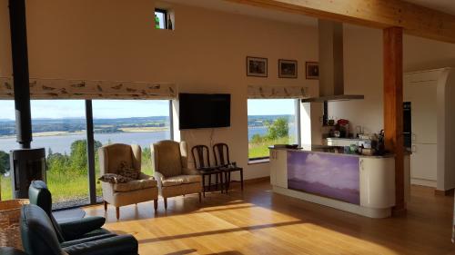 a living room with a large television and a kitchen with windows at Wester Blackpark Farm in Inverness