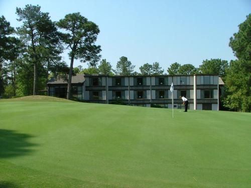 a man standing on a golf green with a building in the background at The Inn at Houndslake in Aiken