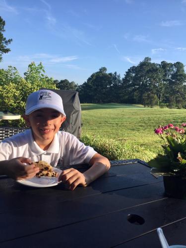 a young boy sitting at a table with a plate of food at The Inn at Houndslake in Aiken