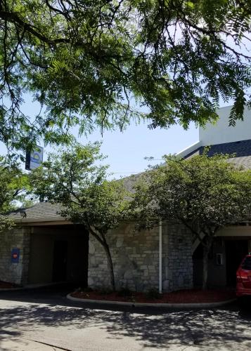 a building with a garage and two trees at Days Inn & Suites by Wyndham Monroe in Monroe