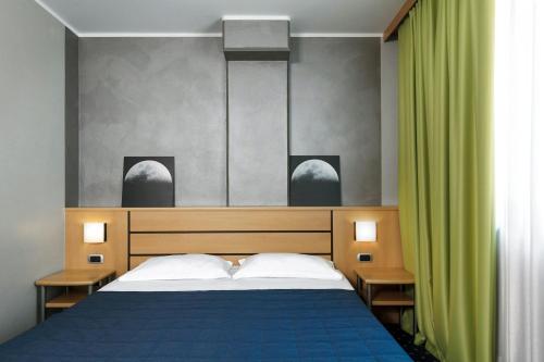 a bedroom with a bed and a green curtain at Garda Hotel in Montichiari