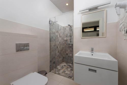 uma casa de banho com um chuveiro, um WC e um lavatório. em Domki Morski Raj em Dębki
