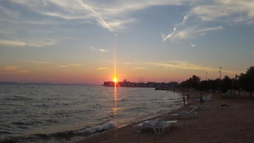 a beach with chairs and the ocean at sunset at Julijana in Zadar