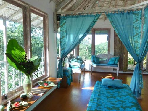 a living room with blue curtains and a couch at Bali Eco Village in Plaga