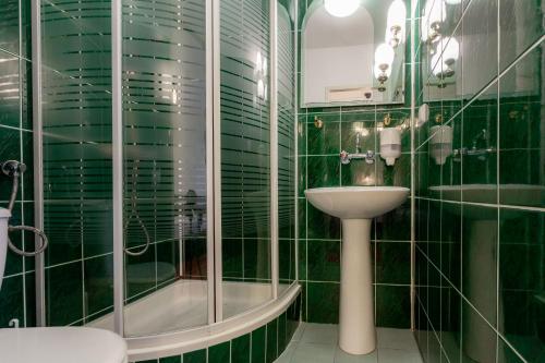 a green tiled bathroom with a sink and a shower at Halny Pensjonat in Zakopane