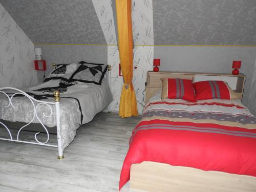 1 dormitorio con 2 camas con almohadas rojas y negras en Le paradis des caves, en Châteauvieux