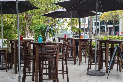 a group of tables and chairs with umbrellas at Hotel Chelsea in Miami Beach