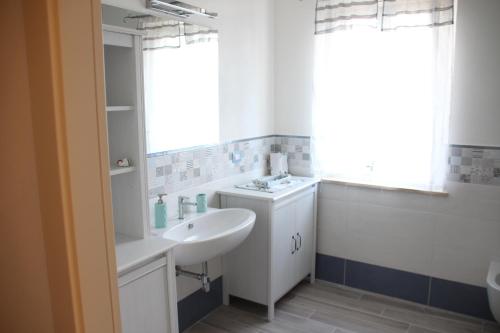 a white bathroom with a sink and a mirror at Carolina Apartment in Rapolano Terme