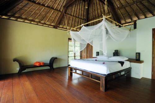 a bedroom with a bed with a mosquito net at Koh Yao Sunrise Villa in Ko Yao Noi