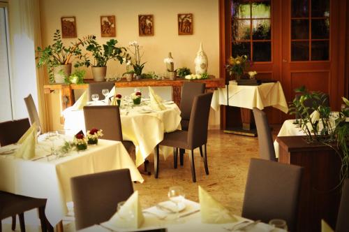 ein Esszimmer mit weißen Tischen, Stühlen und Pflanzen in der Unterkunft Hotel Litjes in Goch