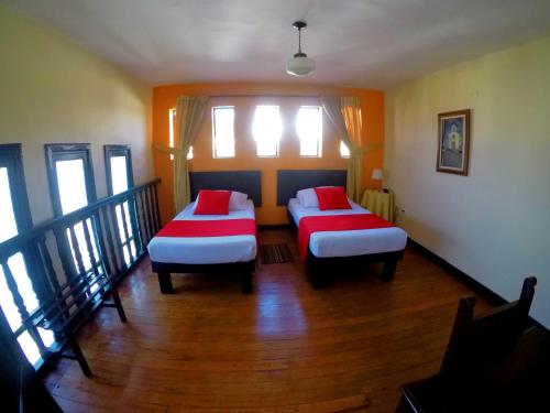 two beds with red pillows in a room at Hotel La Herreria Colonial in Popayan