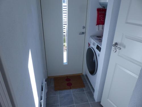 uma pequena casa de banho com uma máquina de lavar roupa e uma porta em Mini-villa 200 m from Kämpinge beach em Höllviken
