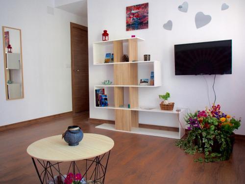 sala de estar con TV, mesa y flores en Apartamento Primavera, en Las Palmas de Gran Canaria