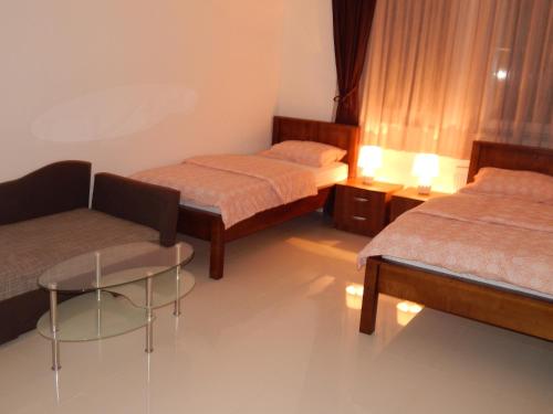 Habitación con 2 camas, silla y mesa. en Apartments S&S, en Konjic