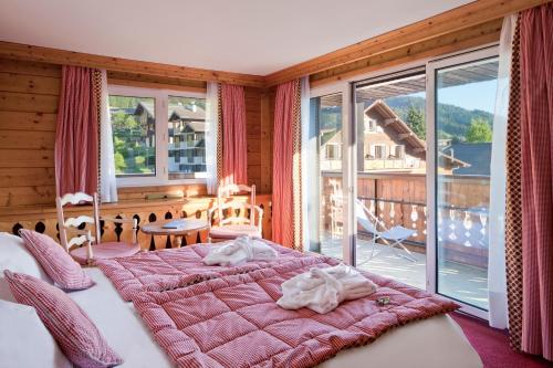 a bedroom with a large bed and a balcony at Chalet-Hôtel La Marmotte, La Tapiaz & SPA, The Originals Relais in Les Gets