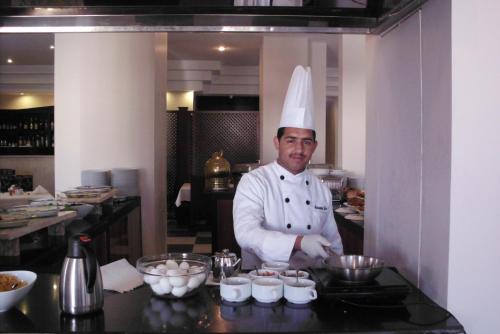 a chef standing in a kitchen preparing food at La Maison Hotel in Wadi Musa