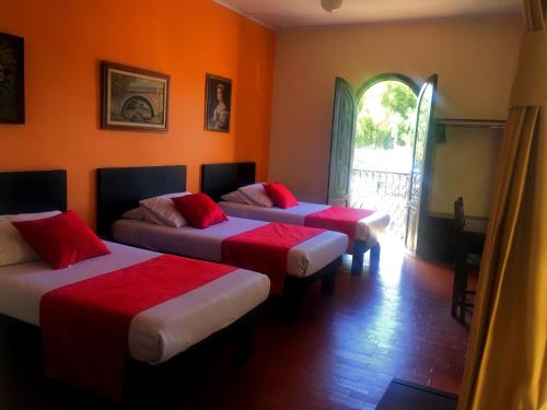 three beds in a room with orange walls at Hotel La Herreria Colonial in Popayan