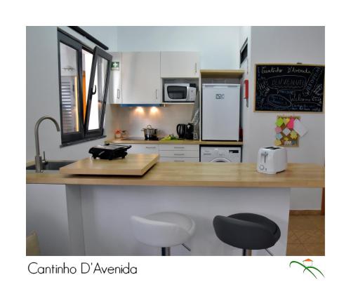 a kitchen with a counter with two stools in it at Cantinho D'Avenida in Velas