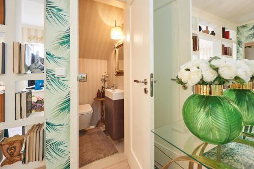 un baño con un jarrón verde con flores blancas. en Luxurious triplex near the beach In Estoril, en Estoril