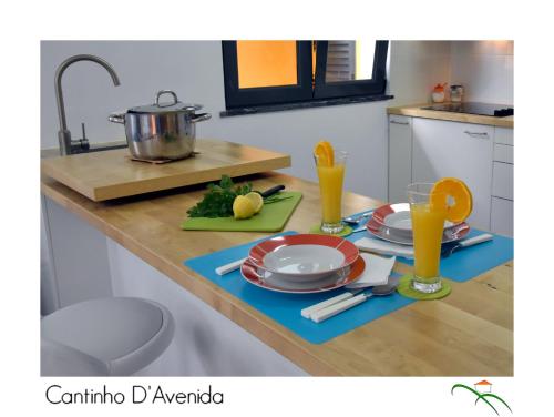 a kitchen counter with plates and glasses of orange juice at Cantinho D'Avenida in Velas