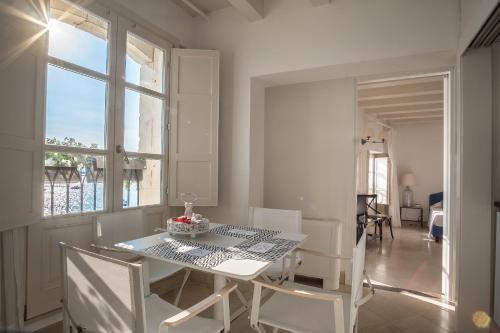 a white dining room with a table and chairs at Palazzo Alfeo Aparthotel in Siracusa