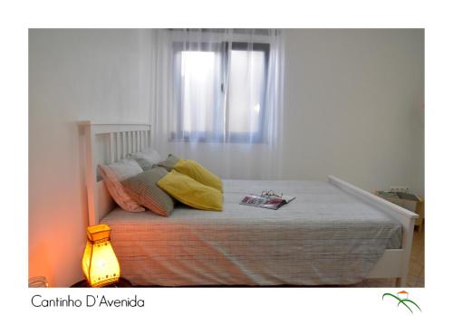 a bedroom with a bed with pillows and a window at Cantinho D'Avenida in Velas