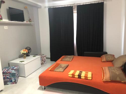 um quarto com uma grande cama laranja e cortinas pretas em Garsoniera Aleea Trandafirilor em Băile Herculane