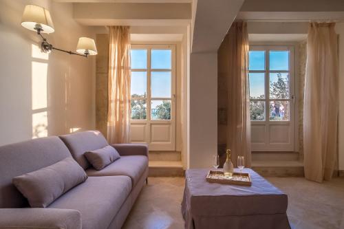 a living room with a couch and two windows at Palazzo Alfeo Aparthotel in Siracusa