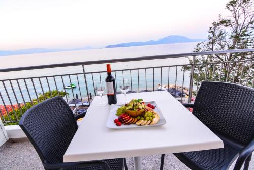 a table with a plate of fruit and a bottle of wine at Marzi Boutique Hotel in Nerátza