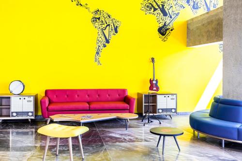 a living room with a red couch and a yellow wall at Ibis Styles Merida Galerias in Mérida